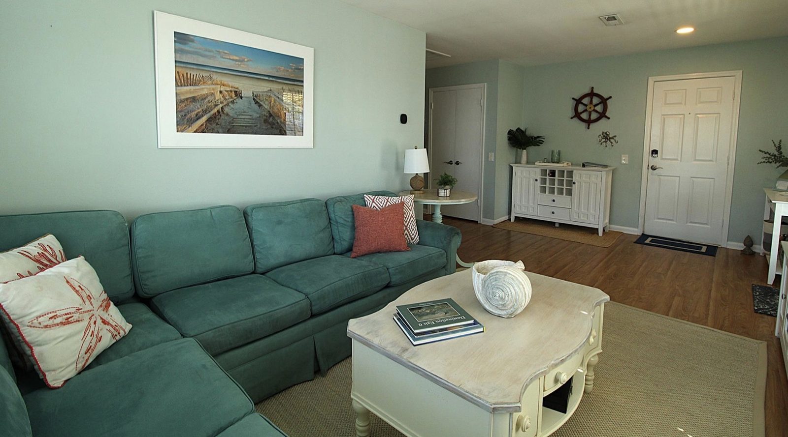 Living room with sectional sofa, coffee table, and coastal art